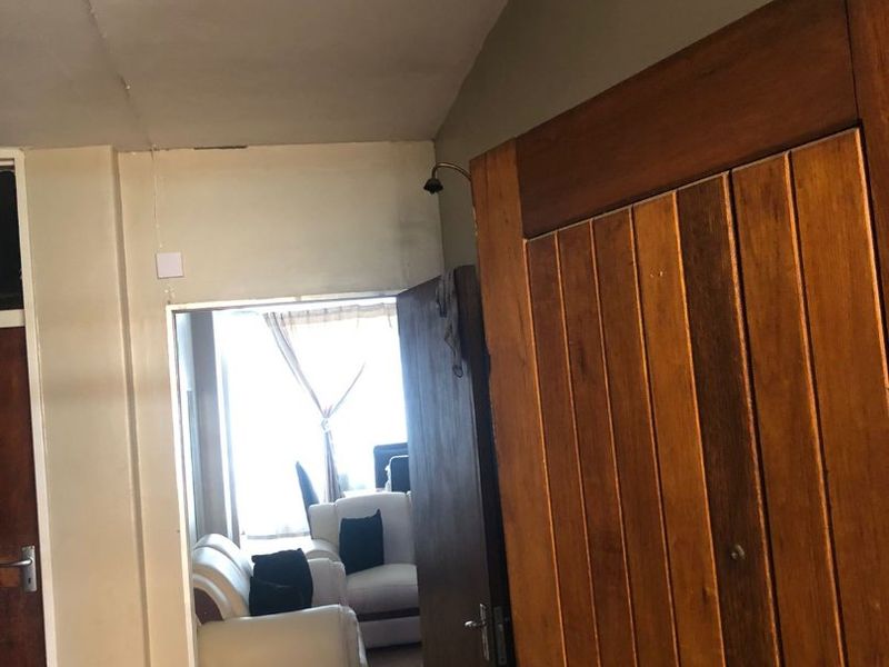 View of an apartment entrance featuring a solid wood door and visible ceiling and wall finish wear.