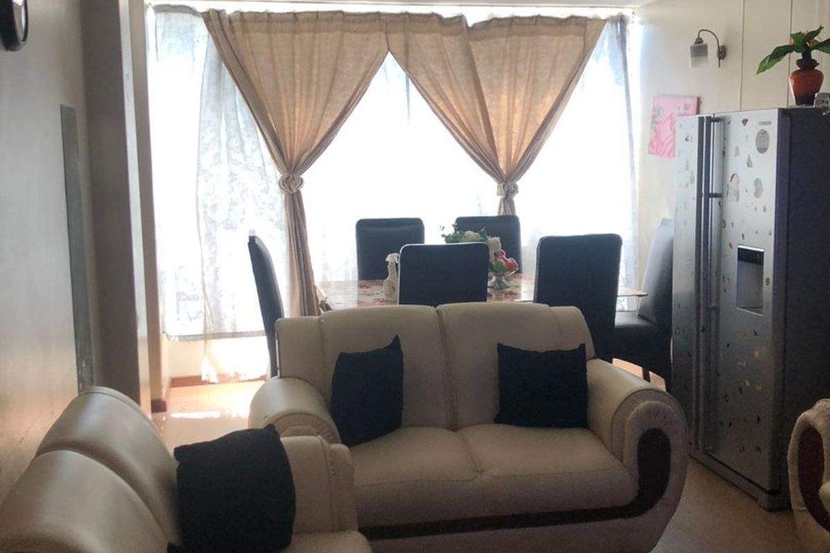 Open plan living and dining area featuring tiled flooring and a large window, providing a functional space with potential for cosmetic updates.