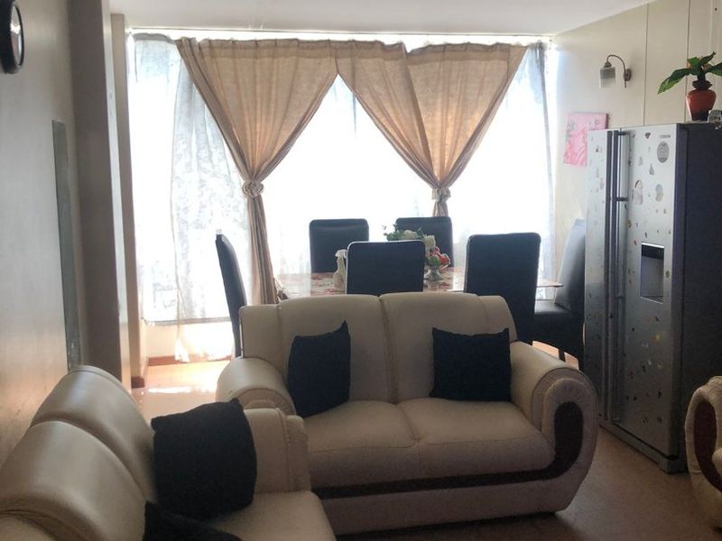 Open plan living and dining area featuring tiled flooring and a large window, providing a functional space with potential for cosmetic updates.