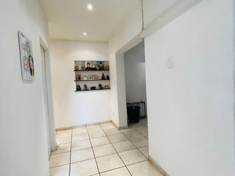A bright, tiled hallway featuring a built-in wall niche and recessed lighting, providing a clean transition space between rooms.