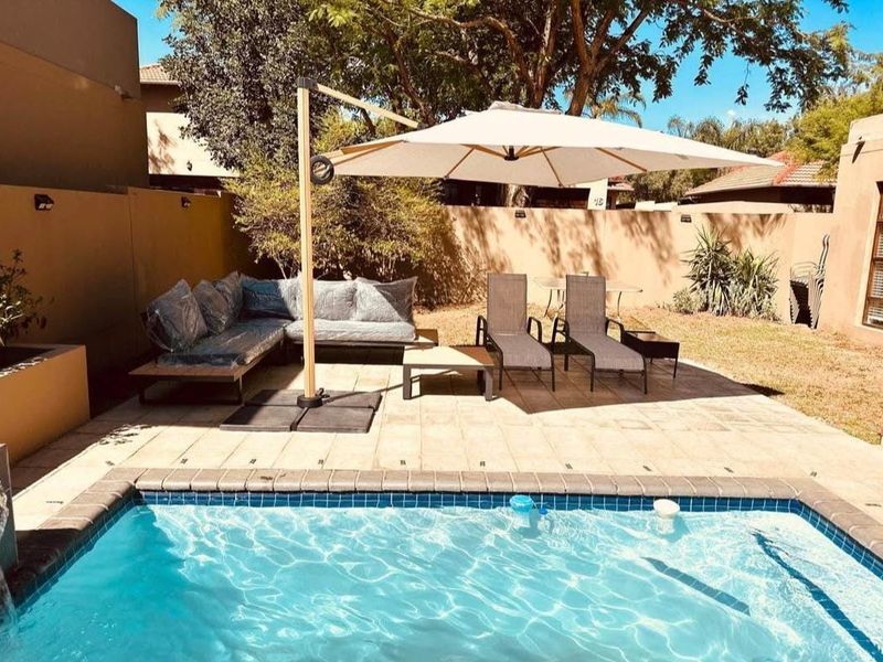 A private outdoor pool area featuring a paved patio space, ideal for relaxation and outdoor entertainment within a secure boundary wall setting.