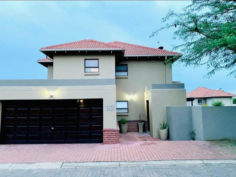 Front elevation of a modern two-story house featuring a tiled roof, paved driveway, and an integrated double garage.