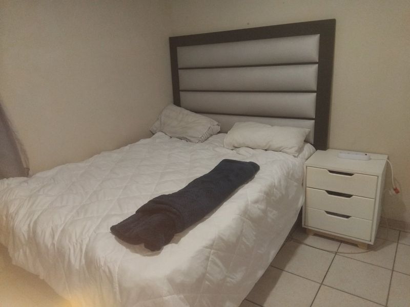 A bedroom featuring tiled flooring and a built-in headboard, providing a functional space for rest.