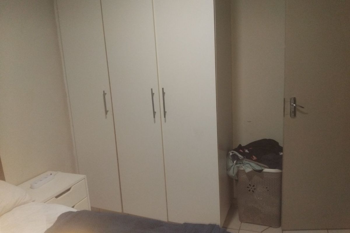 A bedroom featuring built-in cupboards and tiled flooring, providing functional storage space within the room.