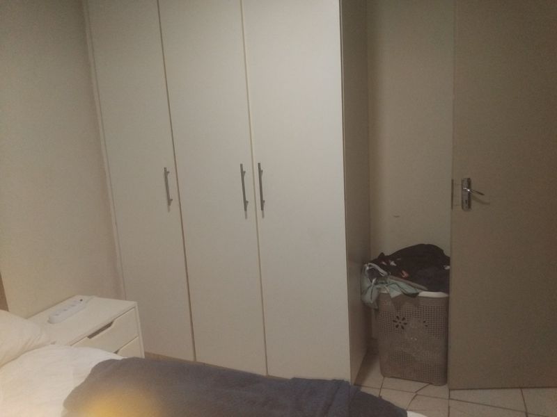 A bedroom featuring built-in cupboards and tiled flooring, providing functional storage space within the room.
