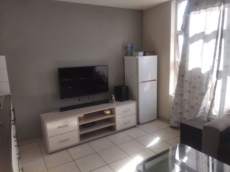 Open plan living area featuring tiled flooring and a large window allowing natural light into the space.