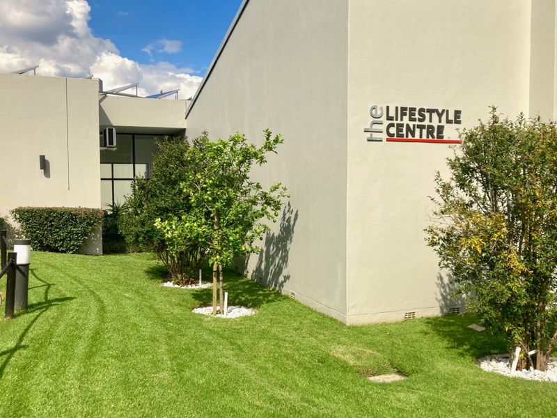 Exterior view of the apartment complex lifestyle centre featuring manicured lawns, paved pathways, and modern building signage.