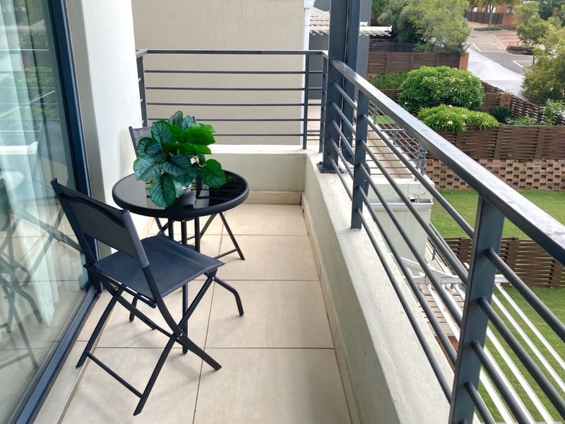 A well-maintained balcony featuring tiled flooring and a modern metal balustrade, offering an elevated view of the surrounding residential area.