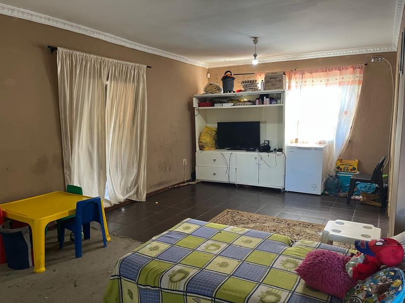 A living room featuring tiled flooring and ceiling cornicing, currently requiring cosmetic updates to the wall finishes.