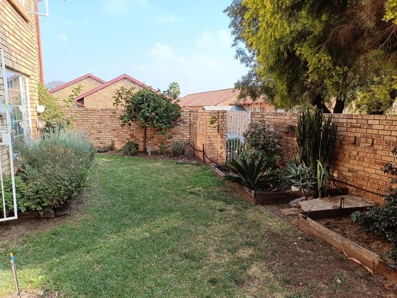 A private rear garden featuring a well-maintained lawn, established landscaping, and secure brick boundary walls.