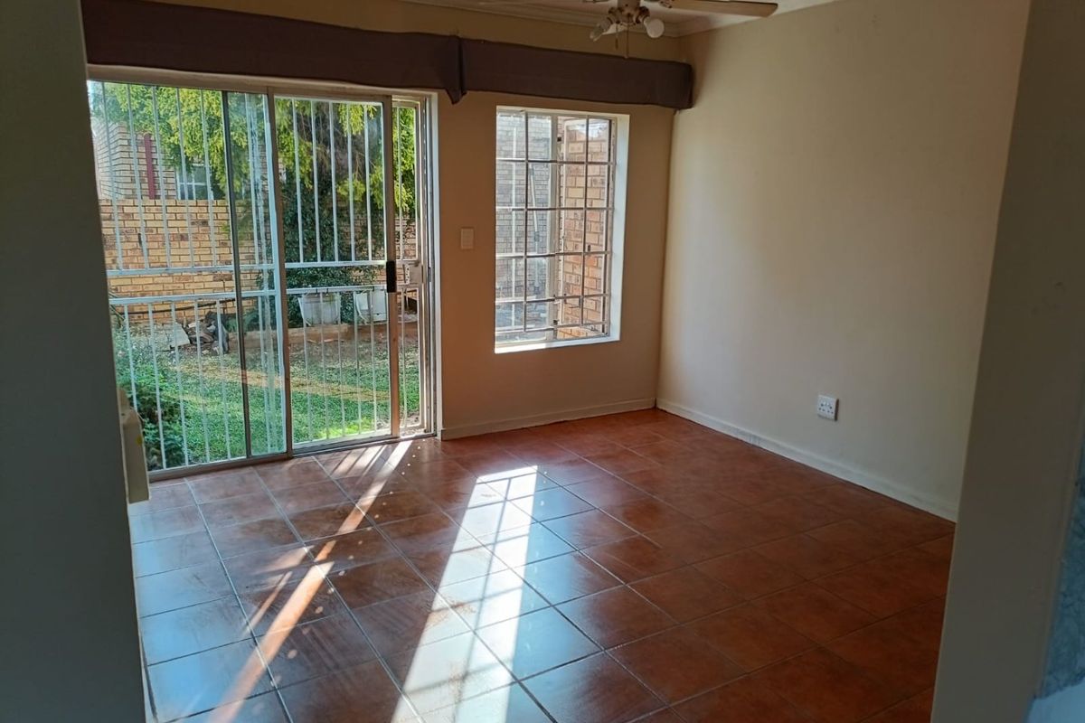 An empty living room featuring ceramic tile flooring, a ceiling fan, and a sliding glass door providing access to the outdoor area.