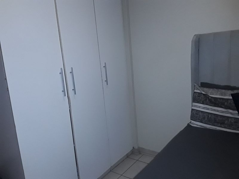 A bedroom featuring built-in cupboards and tiled flooring.