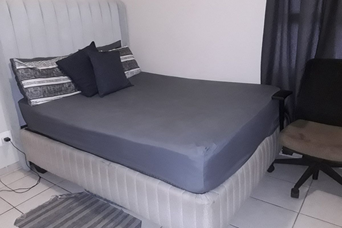 A bedroom featuring tiled flooring and a neutral wall finish, providing a functional space for rest.