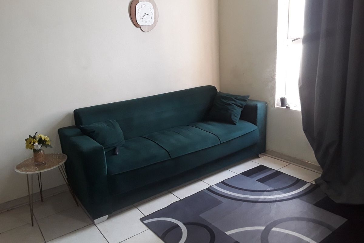 A living room area featuring tiled flooring and natural light from a side window.