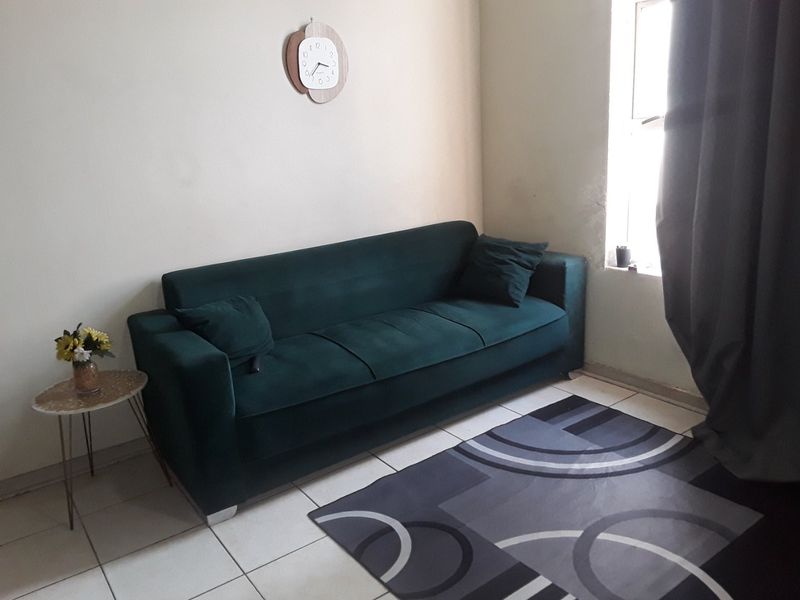 A living room area featuring tiled flooring and natural light from a side window.