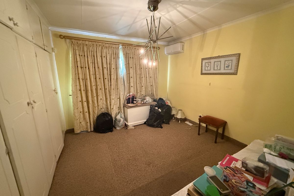 A bedroom featuring built-in cupboards, a split-system air conditioner, and carpeted flooring, offering a functional space ready for modernization.
