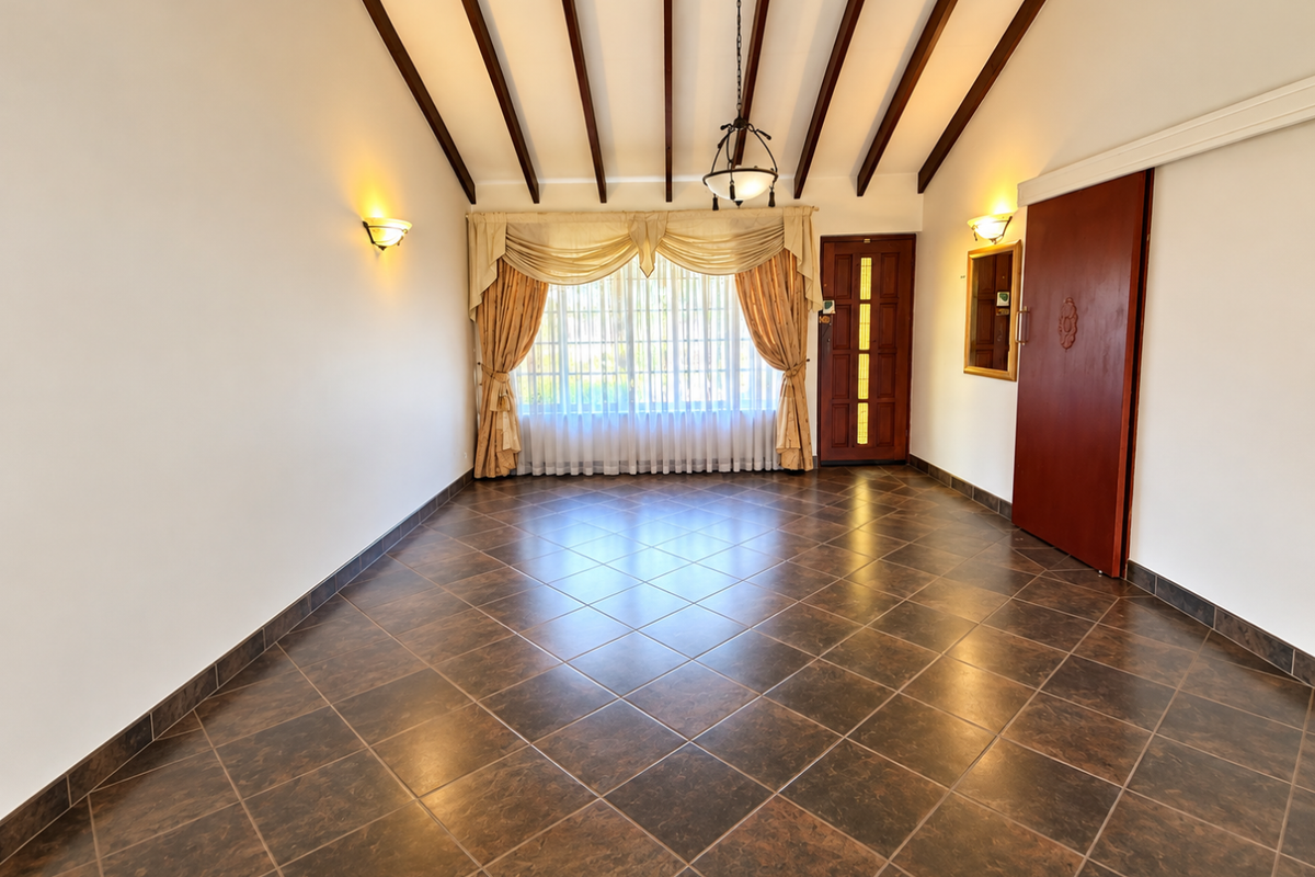 Spacious living area featuring exposed timber ceiling beams, dark tiled flooring, and a sliding door leading to the exterior.