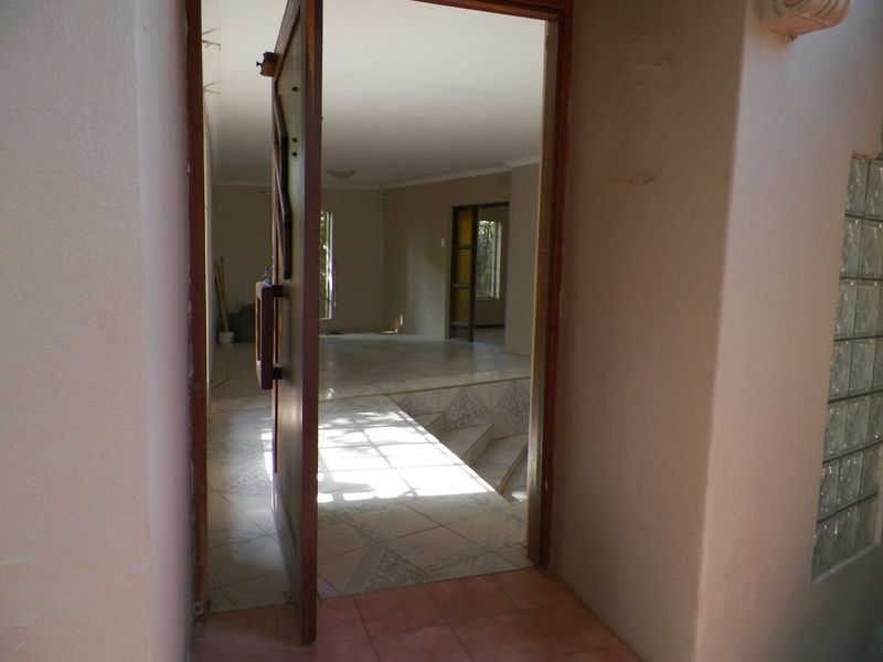 An open entrance area featuring tiled flooring and a glass block feature wall, leading into an empty living space.