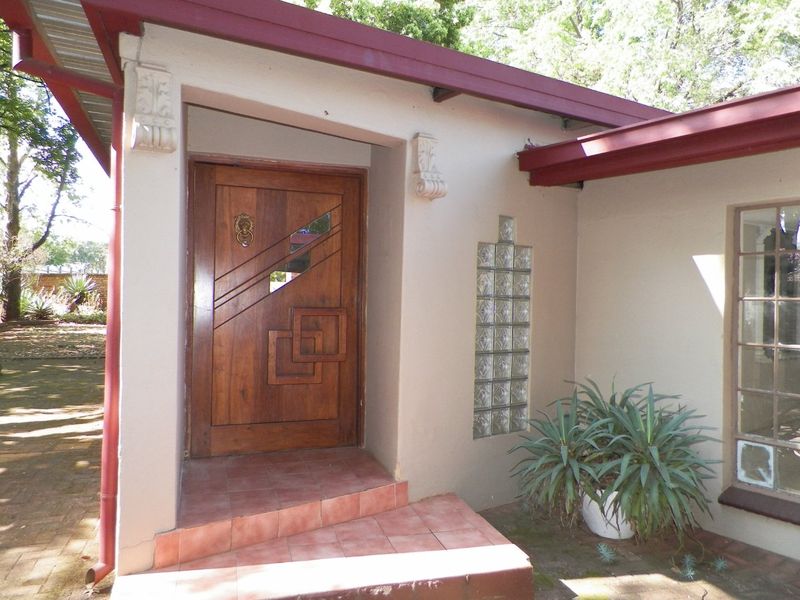 Front entrance featuring a decorative solid wood door, glass block accents, and tiled step under a covered porch area.