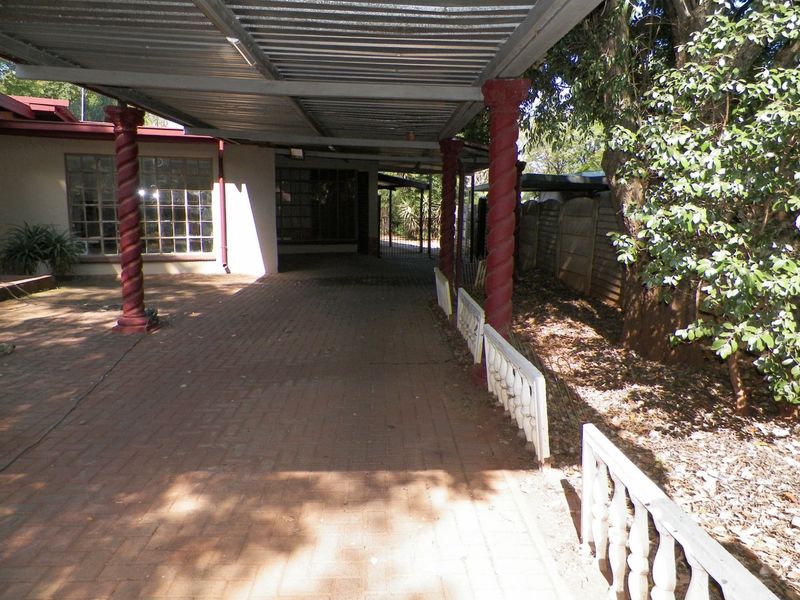 A covered outdoor patio area featuring brick paving, decorative columns, and a metal roof structure, providing a functional space for outdoor living.