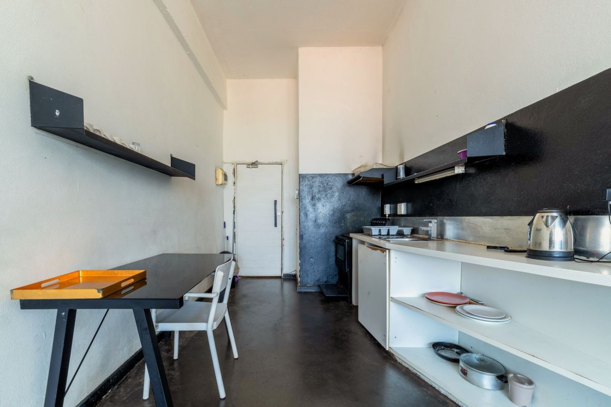 A compact kitchen area featuring built-in shelving, a sink, and an extractor fan, with a functional layout suitable for renovation.
