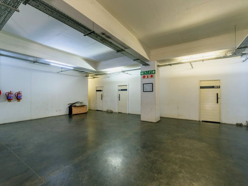 A functional utility or storage area featuring concrete flooring, exposed cable management systems, and essential fire safety equipment.