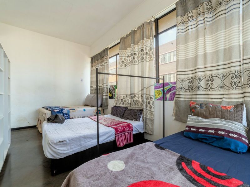 A spacious bedroom featuring large windows that provide ample natural light, complete with built-in shelving and neutral wall finishes.