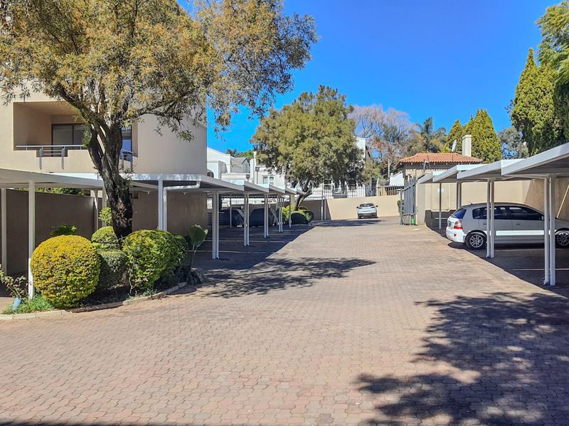 A well-maintained apartment complex parking area featuring paved driveway surfaces and covered carport structures for residents.