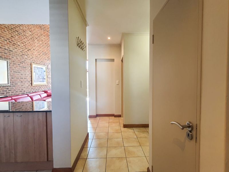 A bright hallway featuring tiled flooring and neutral walls, providing access to adjacent living areas and internal rooms.