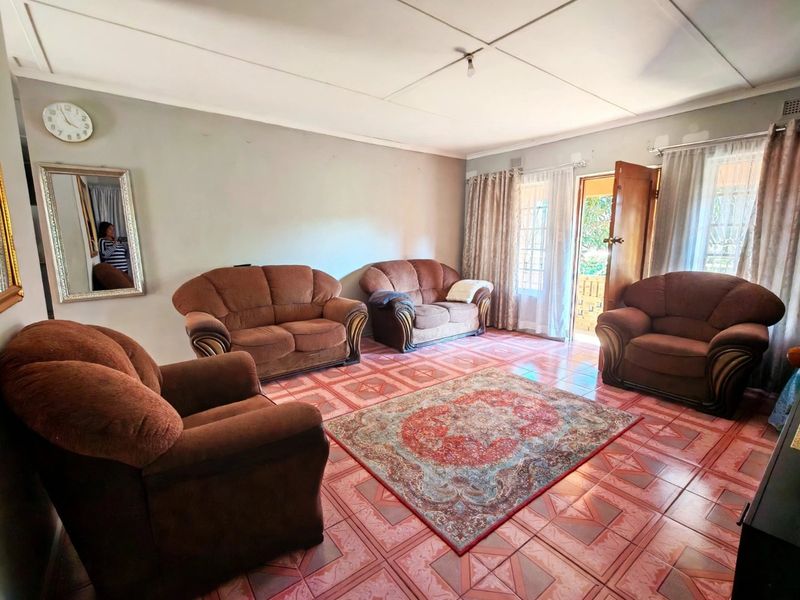 Spacious living room featuring tiled flooring and direct access to the exterior through a security gate.