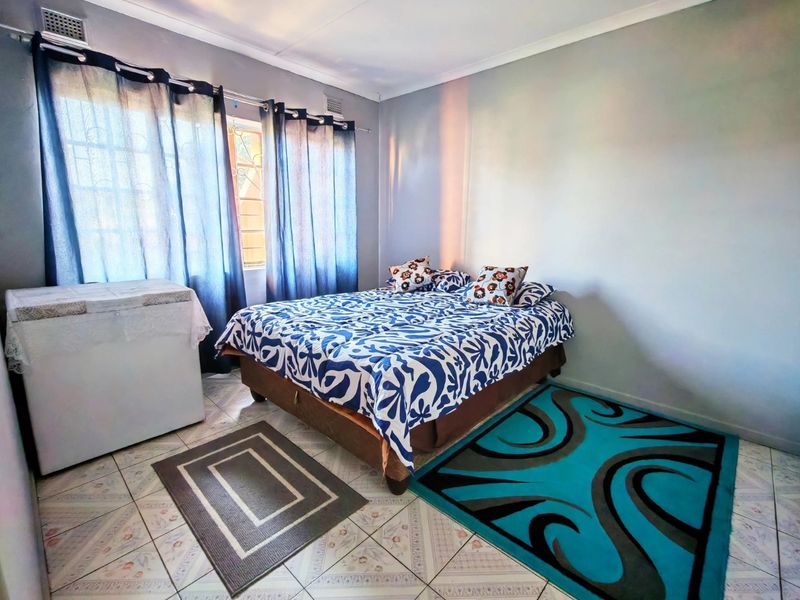 A bedroom featuring tiled flooring, security bars on the window, and neutral wall finishes.