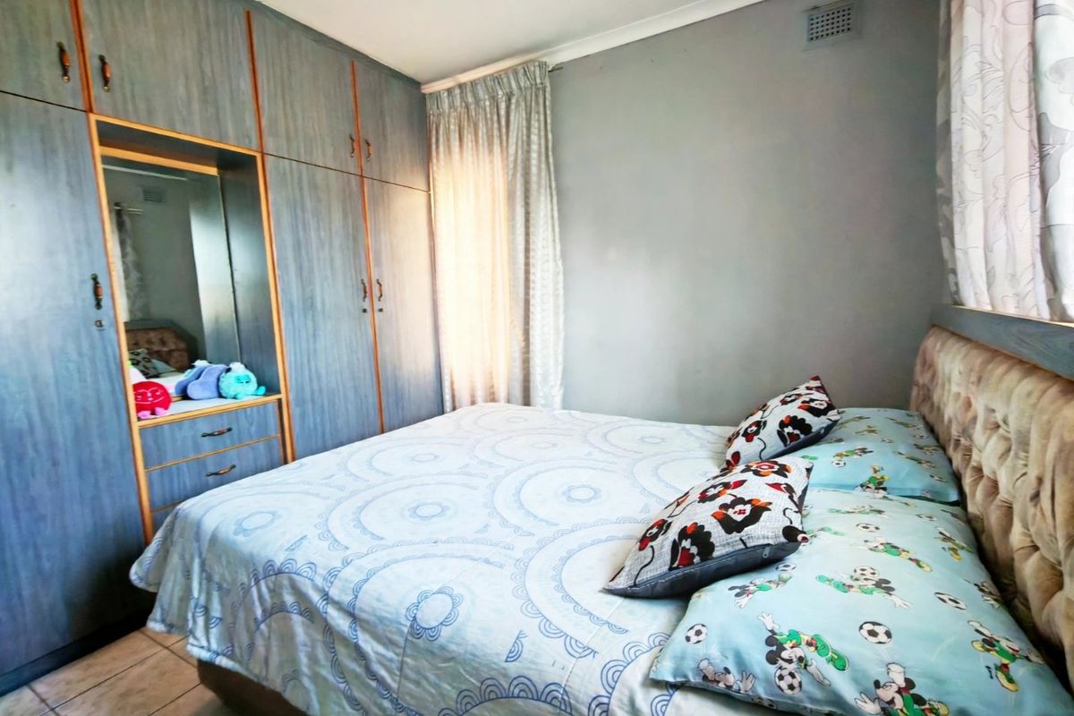 A bedroom featuring built-in cupboards with a mirrored vanity section and tiled flooring.