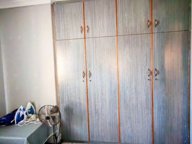 A bedroom featuring floor-to-ceiling built-in cupboards with wood-grain finish cabinetry.