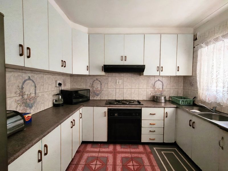 A functional kitchen featuring white cabinetry, laminate countertops, a built-in oven with hob, and a double bowl stainless steel sink.