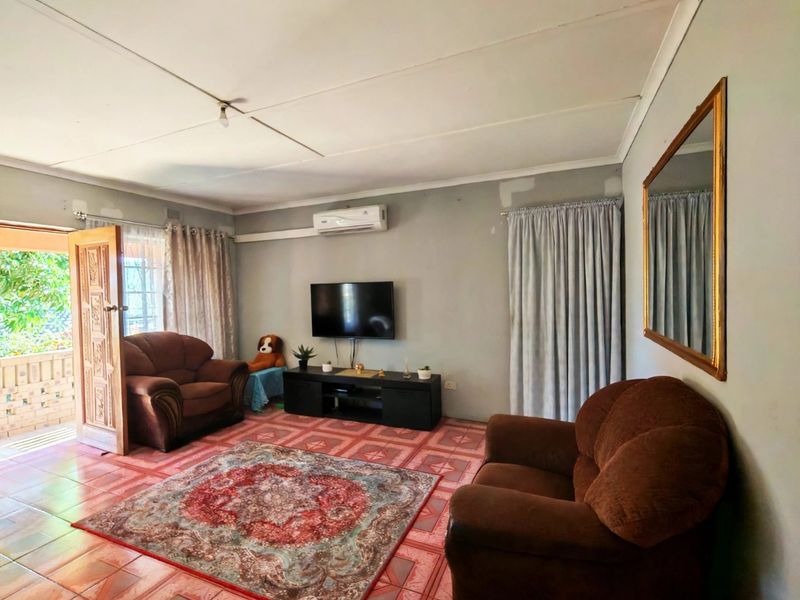 A living room featuring tiled flooring, a split-system air conditioner, and direct access to an outdoor patio area.