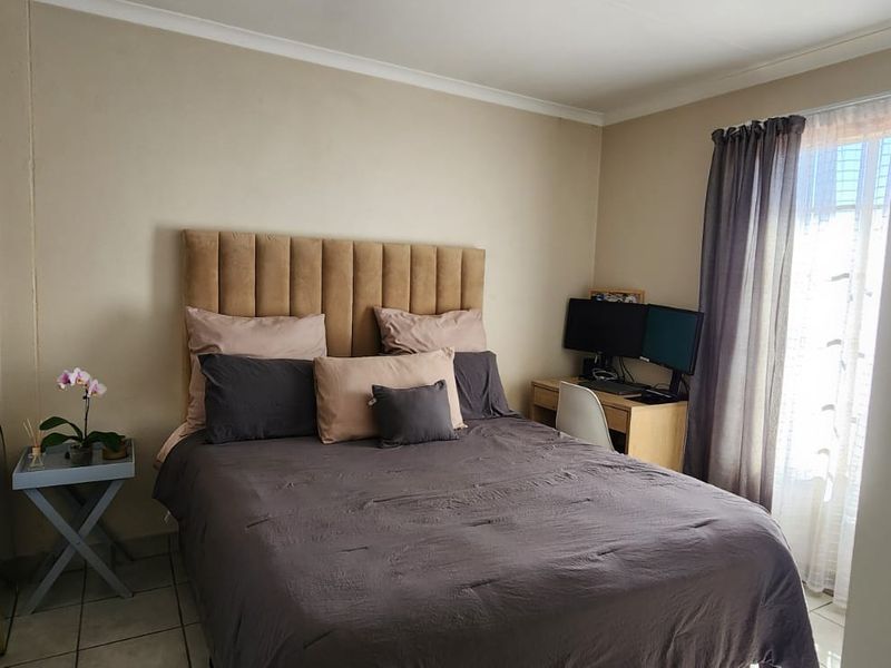 A functional bedroom featuring tiled flooring, cove cornicing, and a sliding door providing natural light access.