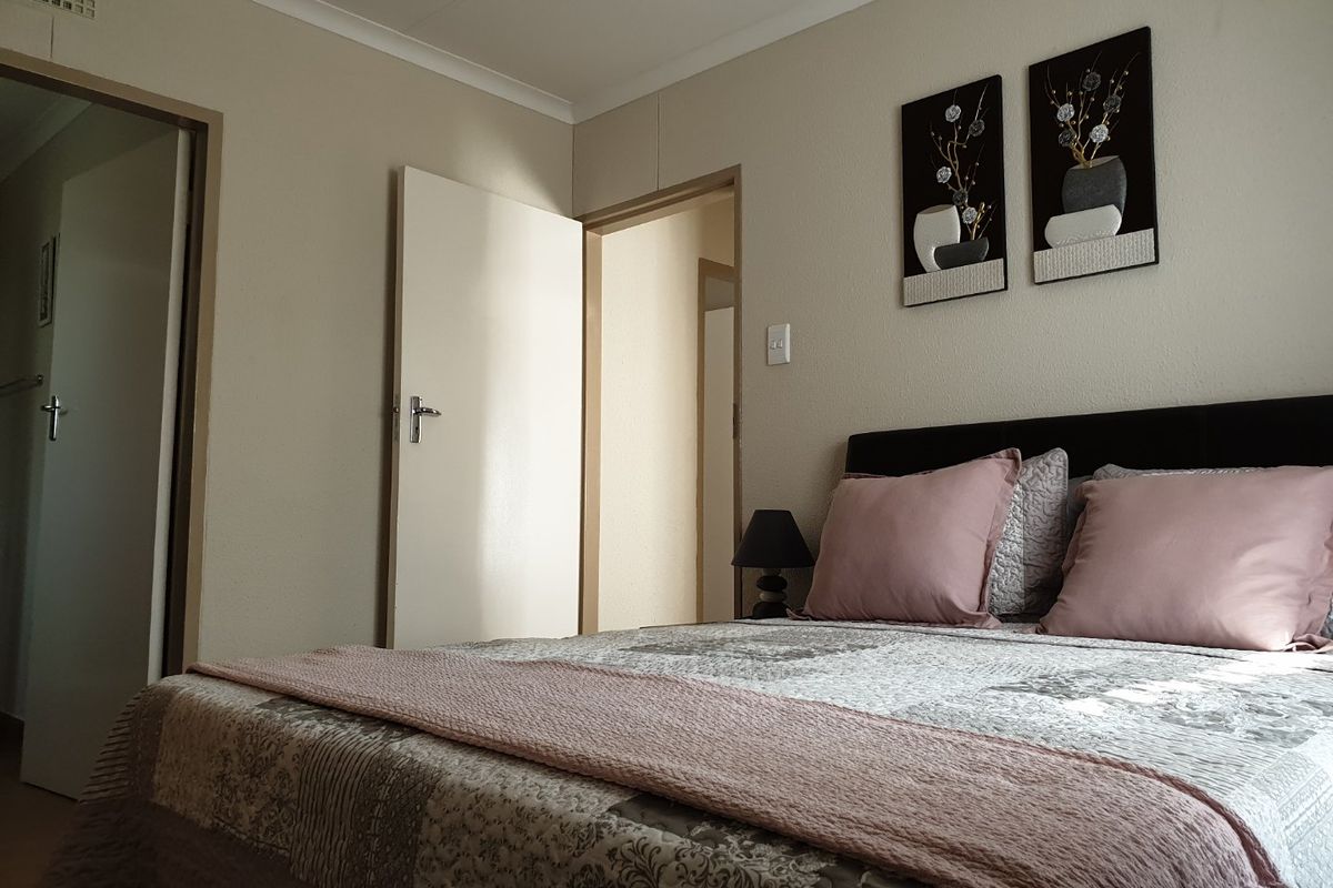 A functional bedroom featuring neutral wall finishes, coving, and multiple doorways leading to adjacent areas of the home.