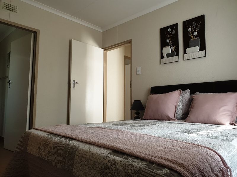 A functional bedroom featuring neutral wall finishes, coving, and multiple doorways leading to adjacent areas of the home.