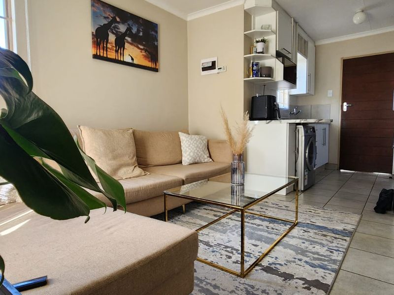 An open-plan living area featuring tiled flooring and a compact, functional kitchen space with built-in cabinetry and shelving.