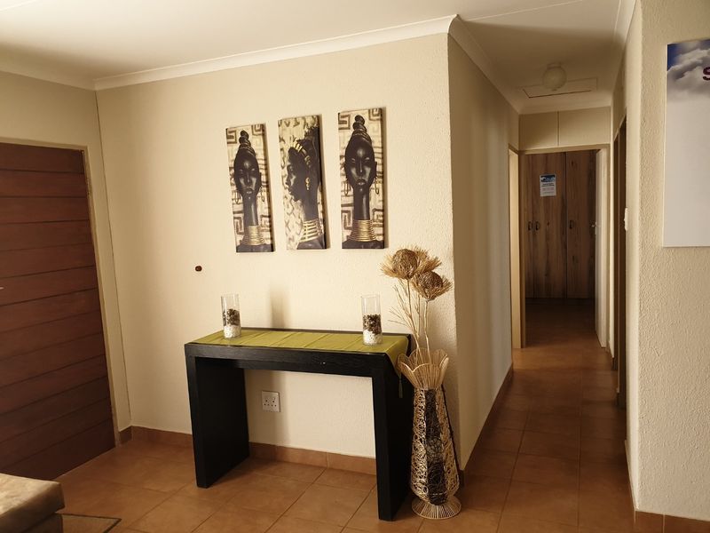 A functional hallway featuring tiled flooring and access to built-in storage cupboards, providing a clean and neutral transition space within the home.