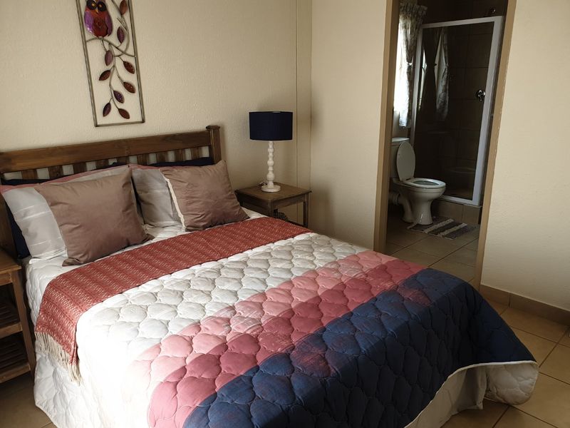 A bedroom featuring tiled flooring and an adjoining en-suite bathroom with a shower and toilet.