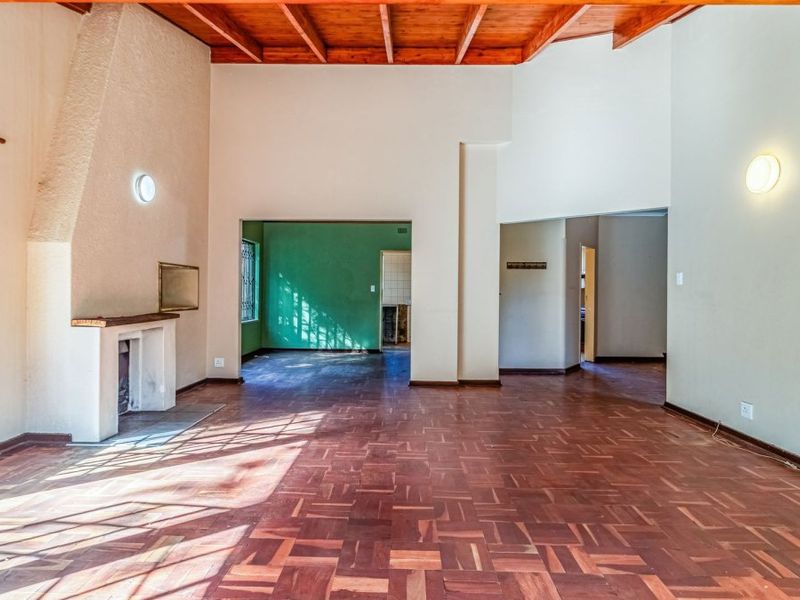 Spacious living room featuring original parquet flooring, exposed timber beam ceilings, and a traditional masonry fireplace, offering a bright and open layout.
