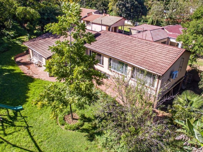 Aerial view of the property showing the tiled roof, exterior walls, and surrounding garden area with mature trees.