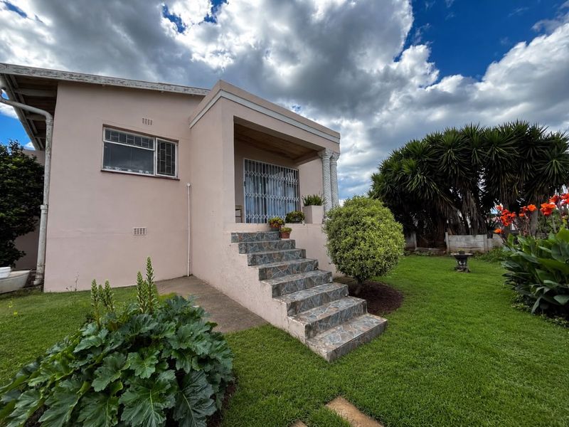 Front elevation of a residential house featuring tiled entrance steps, a security gate, and a well-maintained garden area.