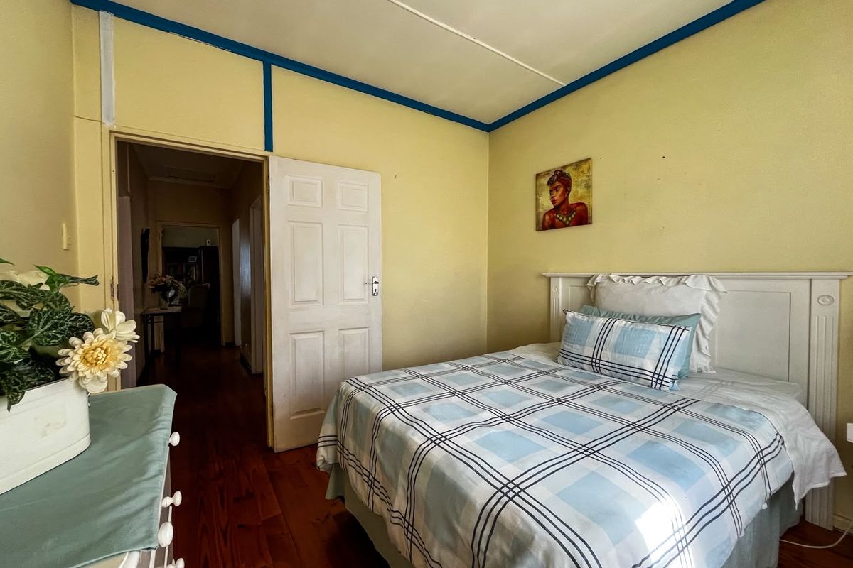 A bedroom featuring original timber flooring and a panelled door, requiring cosmetic updates to the wall finishes and ceiling trim.