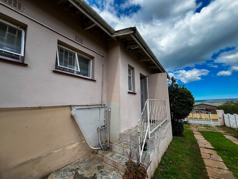 Rear exterior view of the house featuring tiled steps, metal railing, and visible exterior wall finishes requiring maintenance.