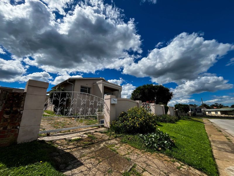 Front view of the property featuring a perimeter wall, wrought iron gate, and paved driveway access.
