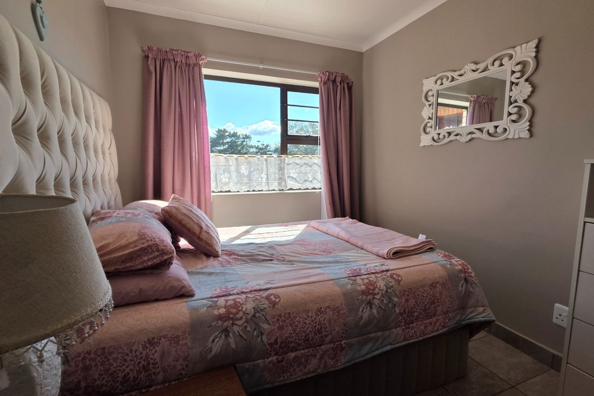 A cozy bedroom featuring tiled flooring, neutral wall tones, and a window providing natural light.