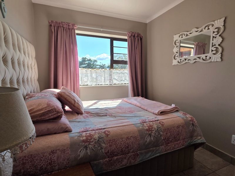 A cozy bedroom featuring tiled flooring, neutral wall tones, and a window providing natural light.