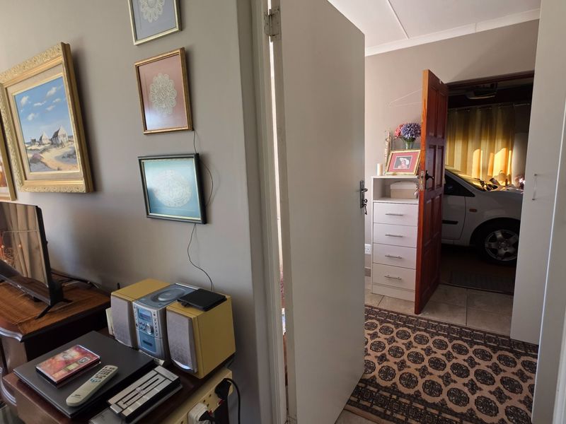 A functional hallway connecting living spaces to the garage area, featuring tiled flooring and standard internal door access.
